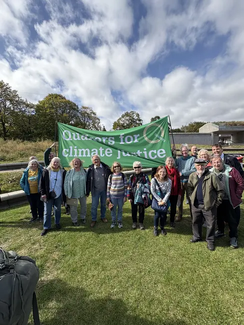 Quakers in Scotland standing under Quakers for climate justice green banner, outside the Scottish Parliament